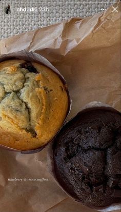 two chocolate muffins sitting next to each other on wax paper