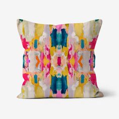 a colorful pillow with an abstract design on the front and back side, sitting on a white surface