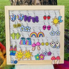 a wooden frame with many colorful earrings hanging from it's sides next to a tree