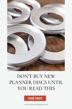 some silver discs on a wooden table with the words don't buy new planner discs until you read this