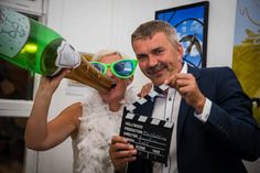 a man and woman posing for a photo while holding up wine bottles