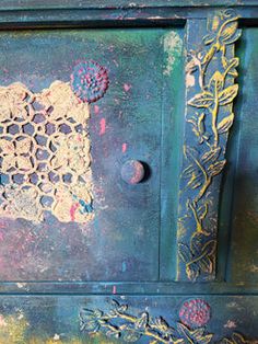 an old blue cabinet with peeling paint and flowers on the door knobs is shown