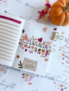 an open planner sitting on top of a table next to pumpkins and other autumn decorations