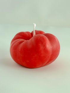 a red tomato sitting on top of a white table