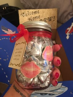 a person holding a jar full of candy and some cards on the side of it