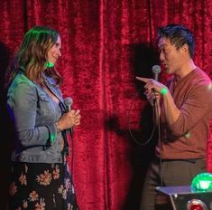 a man and woman standing next to each other in front of a microphone on stage