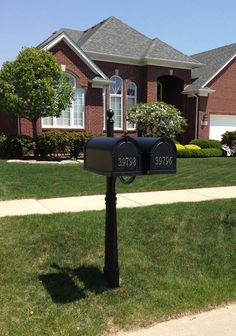 two mailboxes in front of a house on a sunny day with green grass