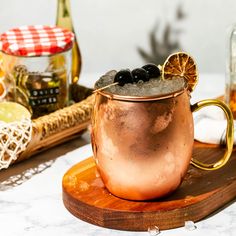 a copper mug filled with black olives and an orange slice