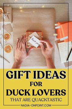 two hands holding a gift box on top of a table with oranges and other items