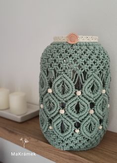 a green crocheted purse sitting on top of a wooden shelf next to candles