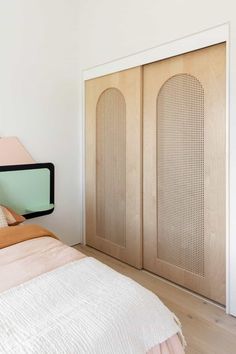 a bed sitting next to a wooden door in a white room with wood flooring