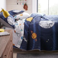 a child's bed with space themed comforter and pillow cases on the side