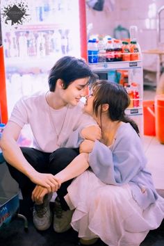 two people sitting next to each other in front of a store display with items on the shelves