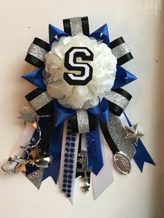 a white and blue ribbon with the letter s on it is attached to a wall