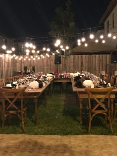 an outdoor dining area is lit up with string lights and wooden tables set for dinner