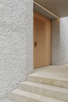 an open door on the side of a white building with steps leading up to it