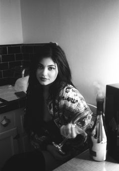 a woman sitting at a kitchen counter with a bottle of wine