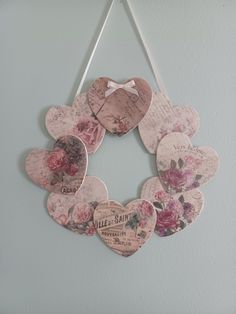 a heart shaped wreath hanging on the wall with flowers and hearts attached to it's sides