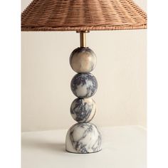 a lamp with three marble balls on it and a wicker shade over the top