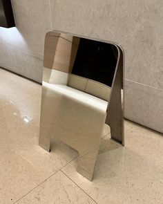 a white chair sitting on top of a tile floor next to a wall with a mirror