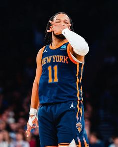 a basketball player holding a ball in his right hand and wiping his face with one hand