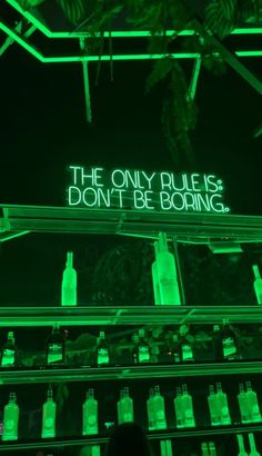 the only rules are don't be boring neon sign in front of liquor bottles