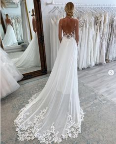 a woman standing in front of a mirror wearing a wedding dress