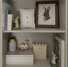 some books and figurines are sitting on the shelves in a bookcase,