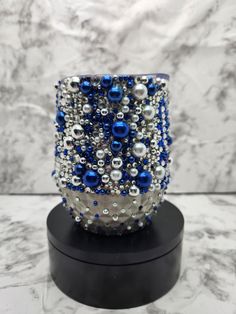 a blue and silver beaded cuff on a black stand in front of a marble wall