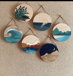 four wooden wall hangings with different designs on them, each featuring an ocean scene