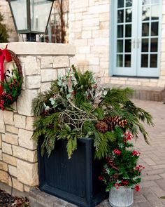 two christmas wreaths are sitting on the side of a brick wall near a lamp post