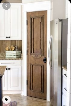 a wooden door in a kitchen next to a refrigerator