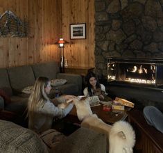 two women sitting on couches in front of a fire place with a dog laying next to them