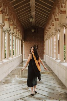 a woman in black dress walking down a walkway