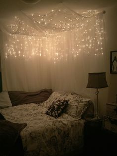 a bed with lights hanging from the ceiling above it and pillows on top of it