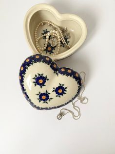 two heart shaped dishes with pearls in the middle one is decorated with blue and orange flowers