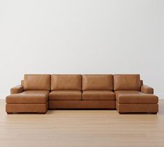 a brown leather couch sitting on top of a hard wood floor next to a white wall