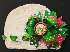 a crocheted hat with a green and pink bow on it's side