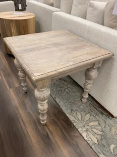 a wooden table sitting on top of a hard wood floor next to a white couch