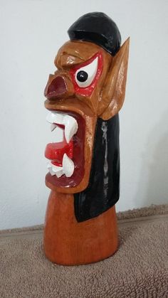 a wooden mask is on the floor next to a white wall and carpeted area