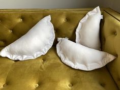 two white pillows sitting on top of a yellow couch