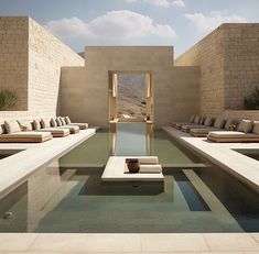 an outdoor swimming pool surrounded by lounge chairs and stone walls, with water running through the middle