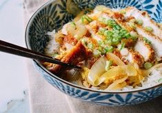 a blue and white bowl filled with rice, meat and veggies next to chopsticks