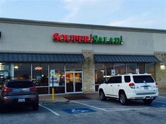 the exterior of a store called sutter salad with two cars parked in front of it