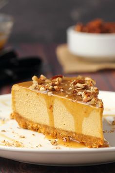 a piece of cheesecake on a white plate with caramel drizzle and nuts