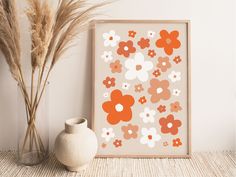 an orange and white flower print sitting next to a vase