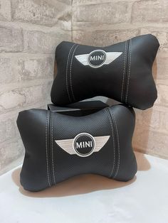 two black leather pillows sitting on top of a white table next to a brick wall