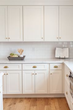 a kitchen with white cabinets and wooden floors