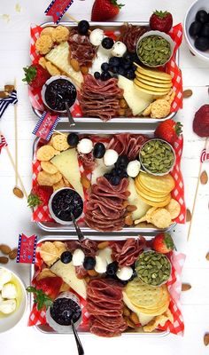 two trays filled with different types of food on top of a white tablecloth