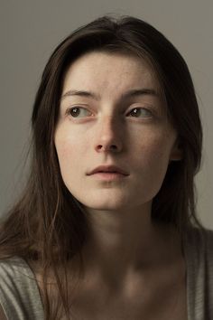 a woman with freckles on her face looks at the camera while posing for a portrait